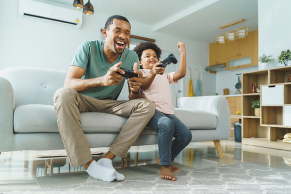 Father and son playing video games in cooled ductless ac home