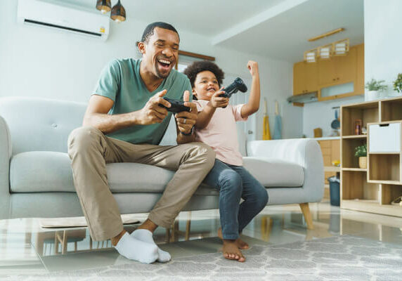 Father and son playing video games in cooled ductless ac home